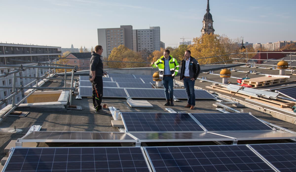 Men stand between a photovoltaic system on a roof