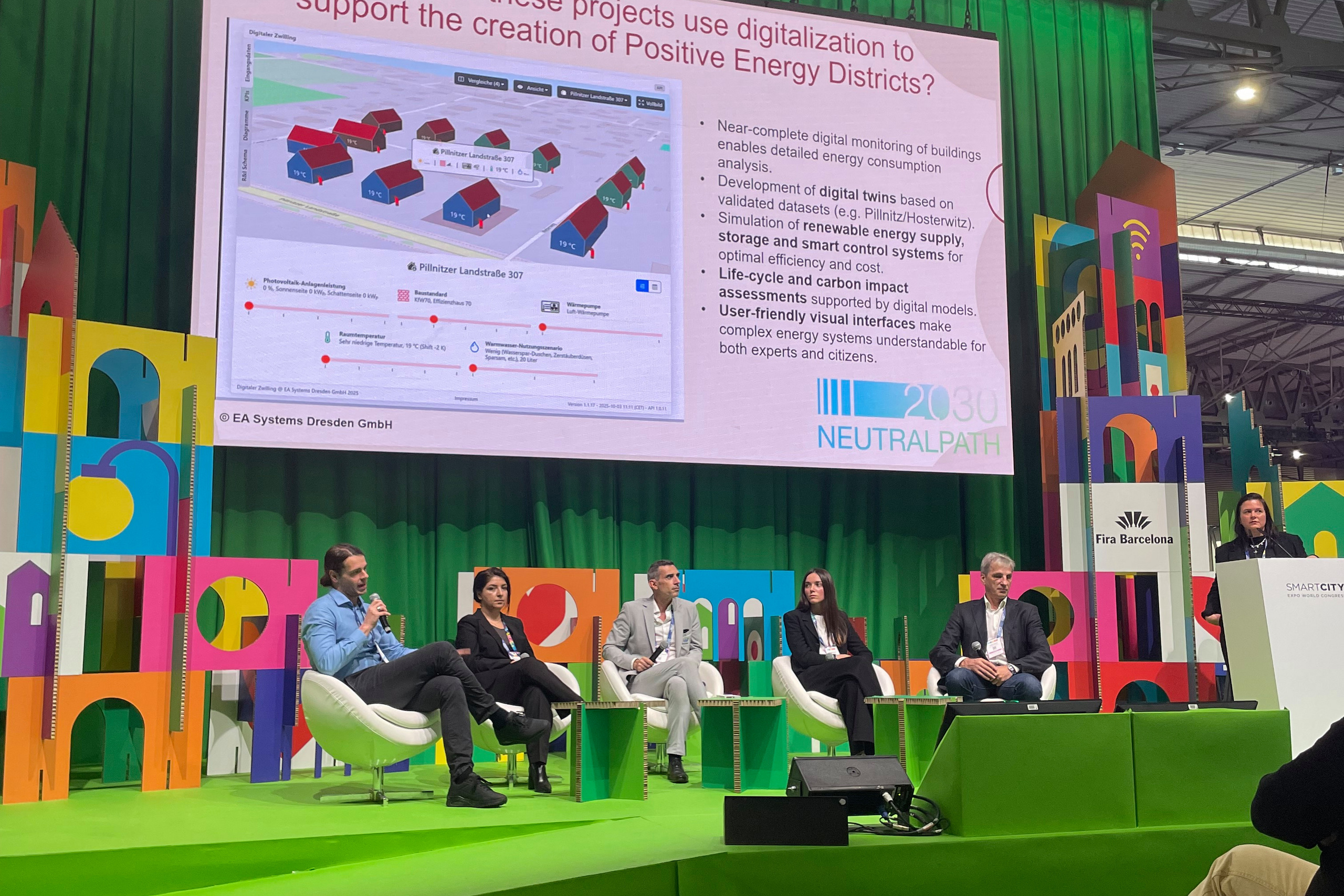 Podiumsdiskussion mit Gästen im Vordergrund und Leinwand im Hintergrund