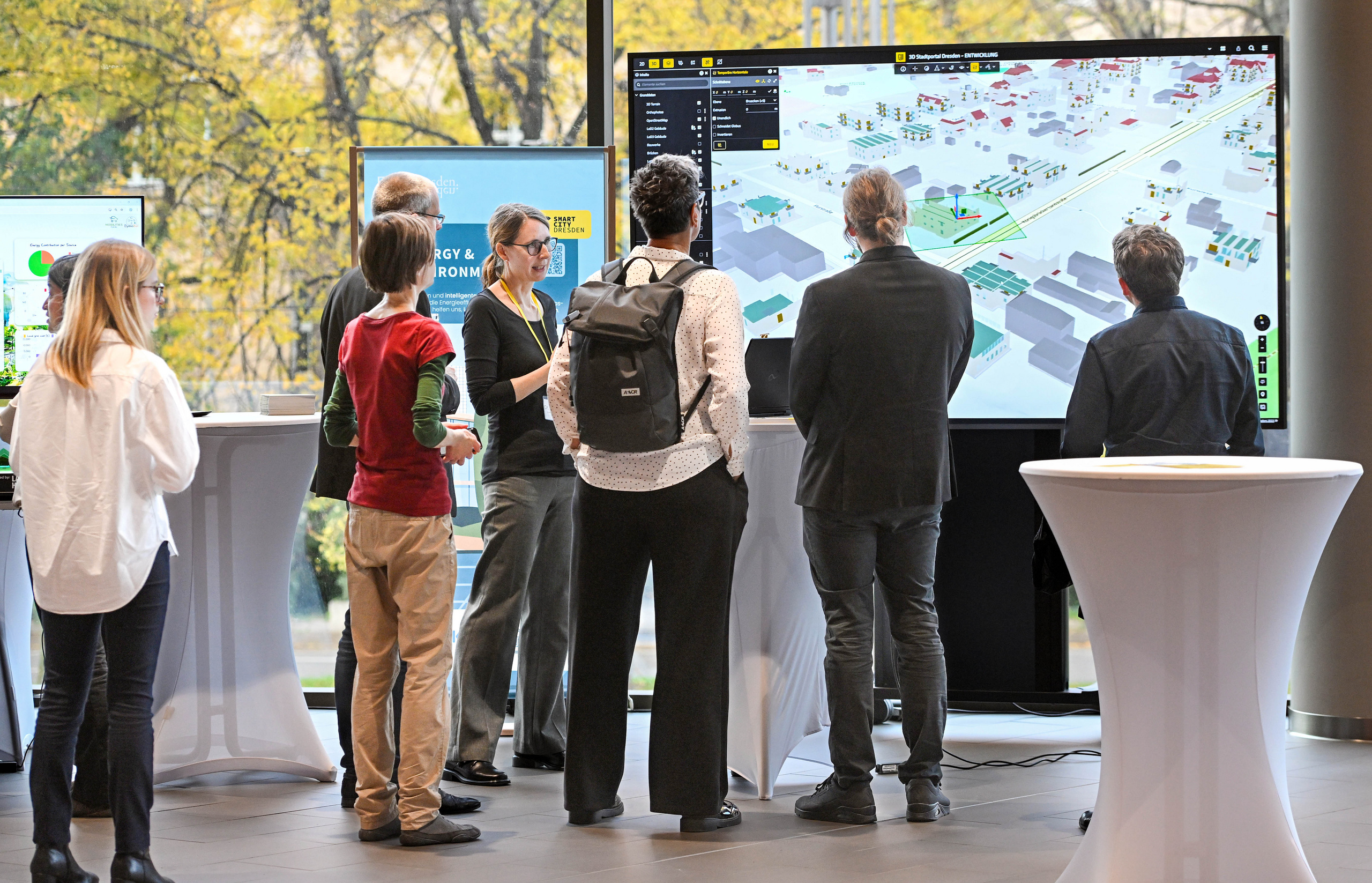Interessierte stehen vor einem Bildschirm mit einem 3D-Stadtmodell