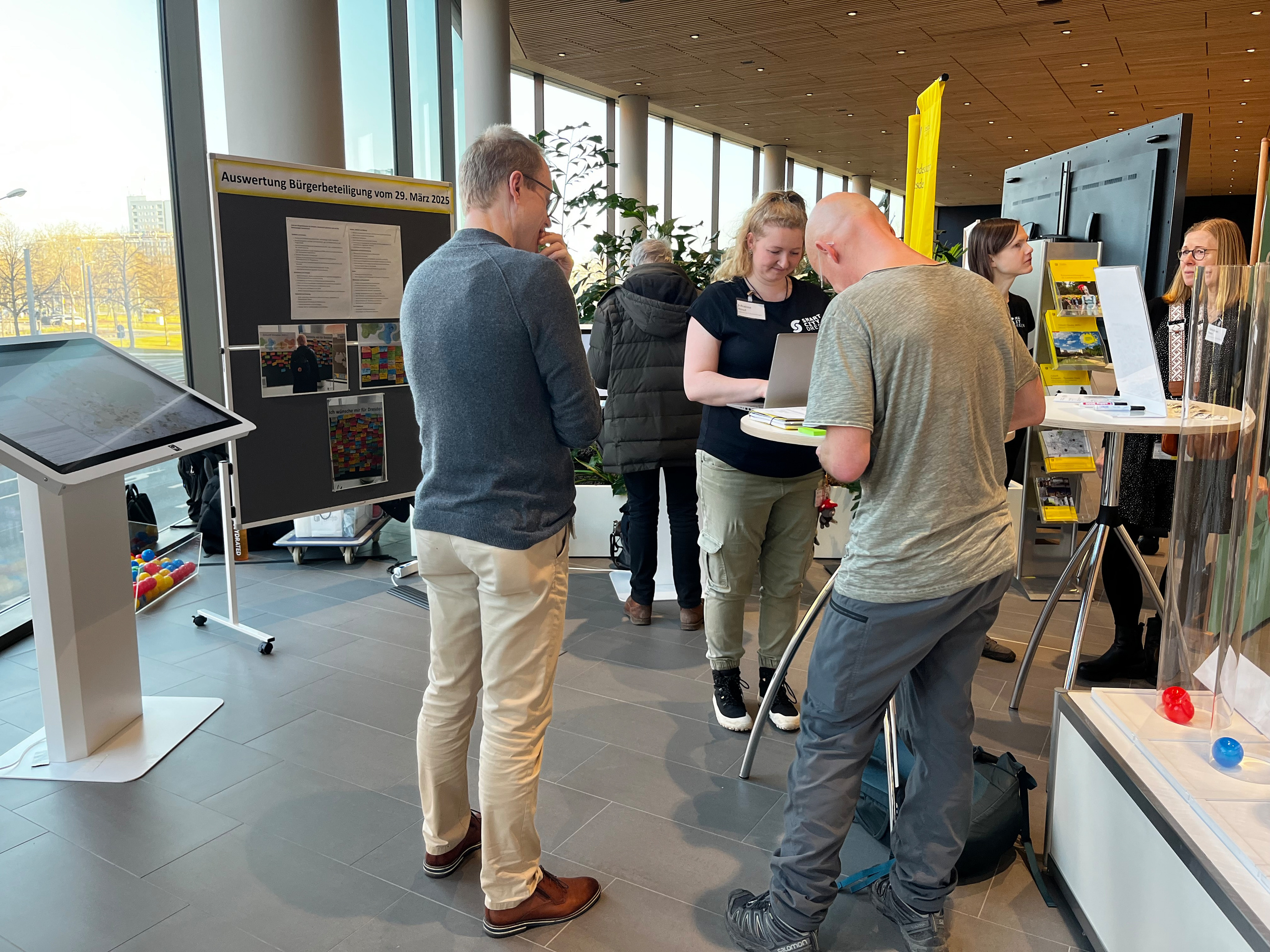Männer und Frauen stehen an einem Informationsstand