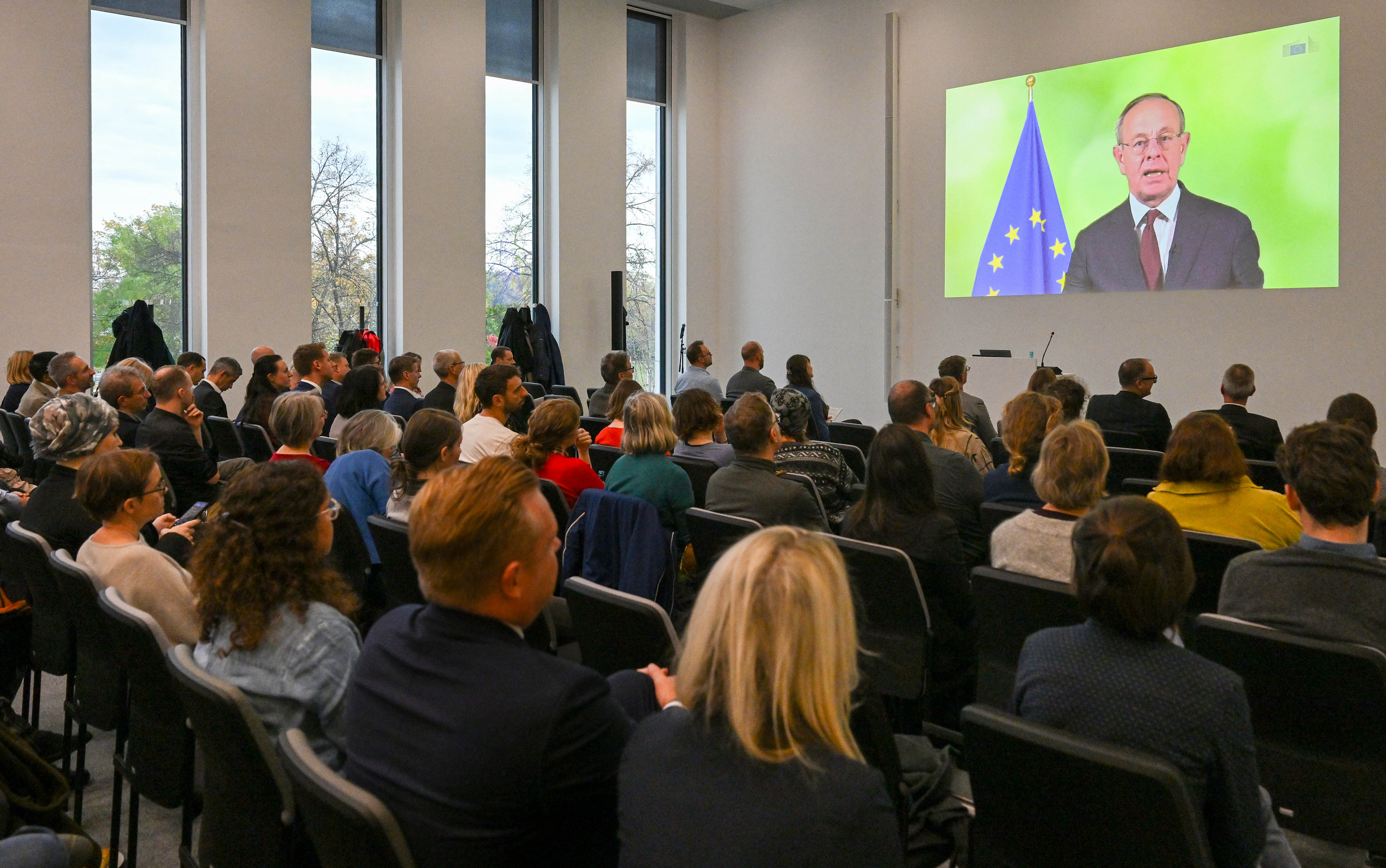 Publikum schaut Videobotschaft auf einer Leinwand