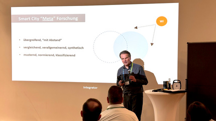 The speaker in front of the audience. A PowerPoint projection with a diagram in the background.