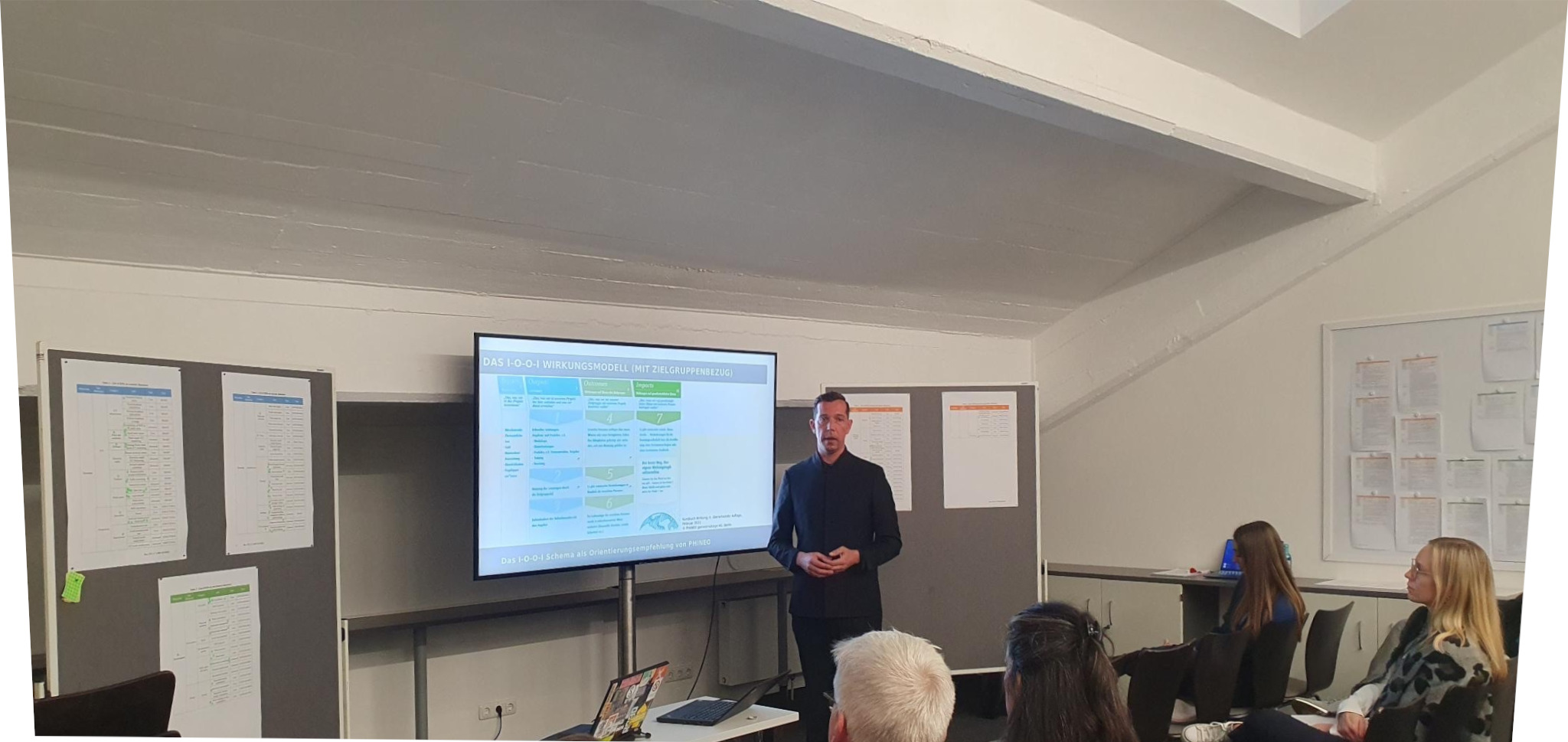 Speaker in front of the screen, audience in front