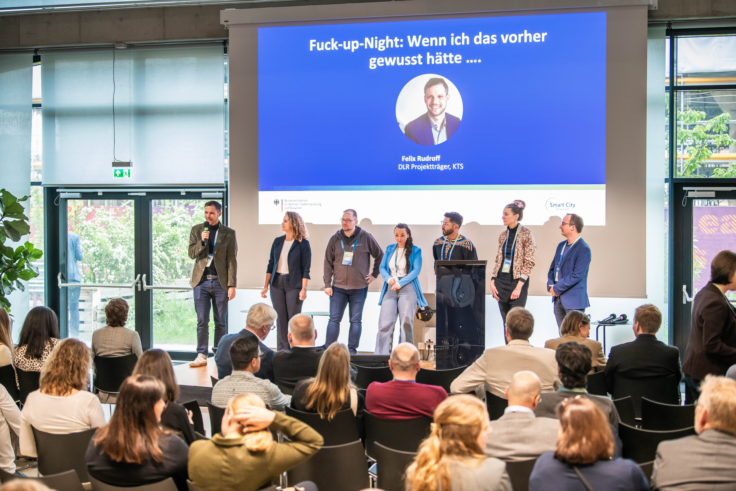 Menschen sitzen im Publikum und schauen auf Menschen auf der Bühne