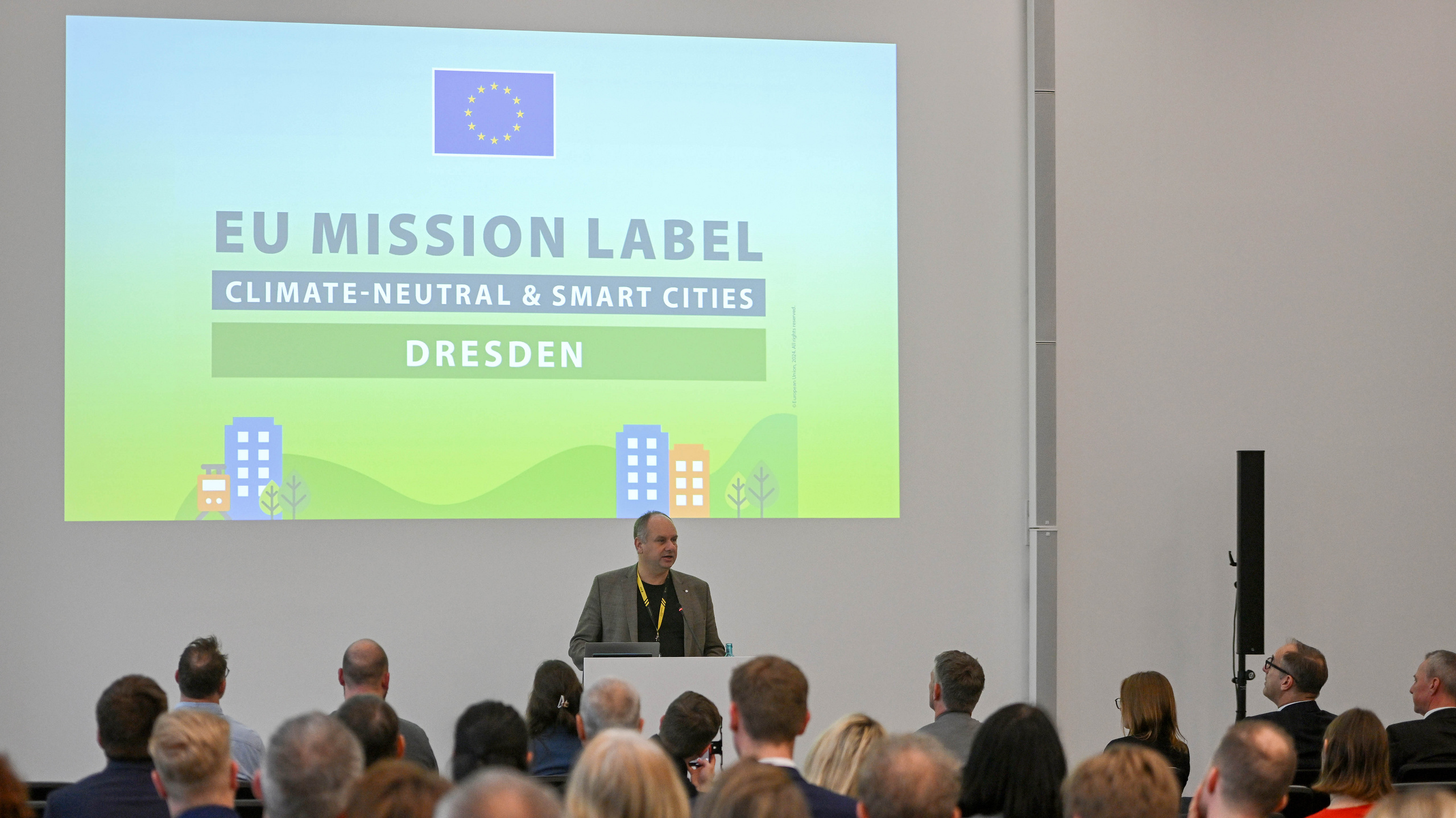 Oberbürgermeister steht an einem Rednerpult mit dem EU Mission Label im Hintergrund