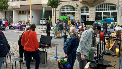 Besucherinnen und Besucher des Stadtfestes sehen auf einen Monitor und einen 3D-Drucker.