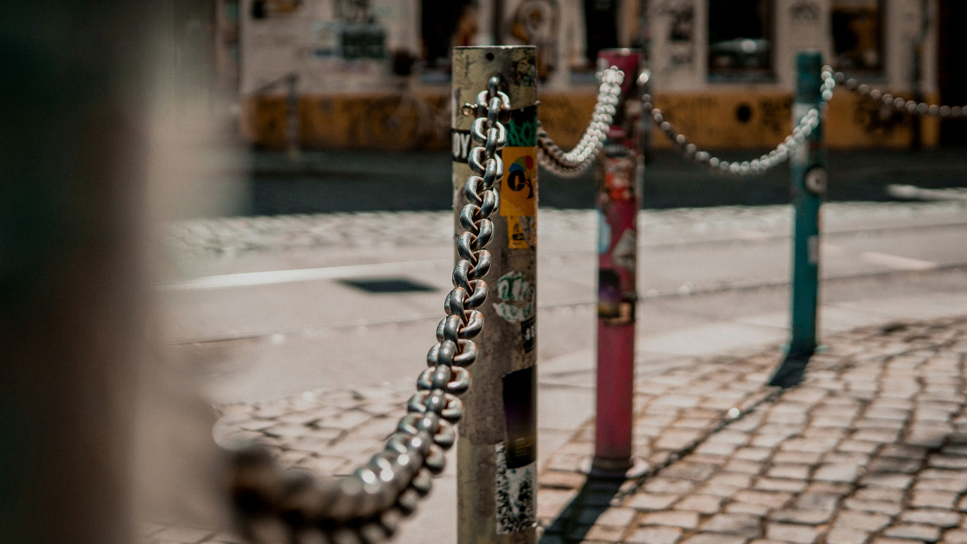 Bunt beklebte Poller mit Ketten verbunden am Straßenrand